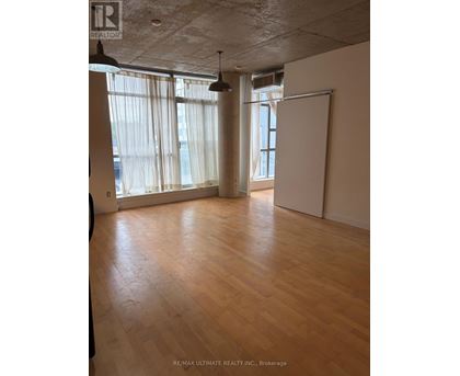A room with wooden floors and a large window with curtains.
