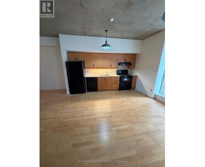A kitchen with wooden floors and a black refrigerator.