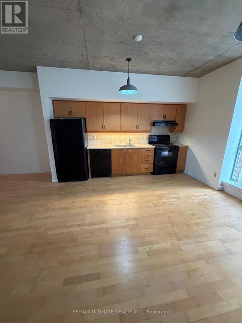 A kitchen with wooden floors and a black refrigerator.