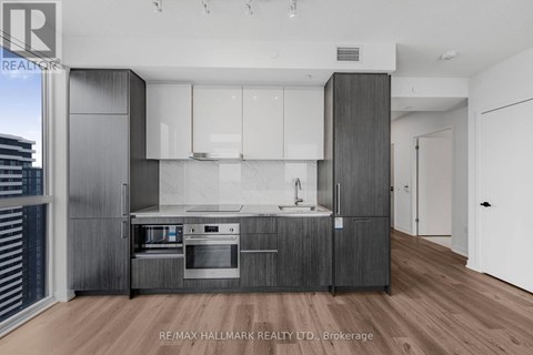 A modern kitchen with white cabinets and a wooden floor.