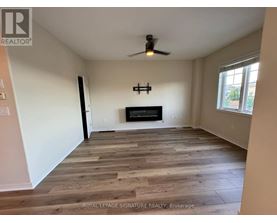 A spacious room with wooden flooring and a fireplace.
