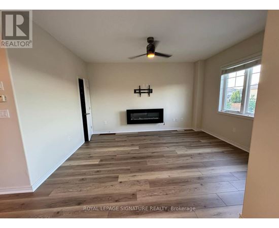 A spacious room with wooden flooring and a fireplace.