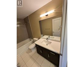 A bathroom with a toilet, sink, and mirror.