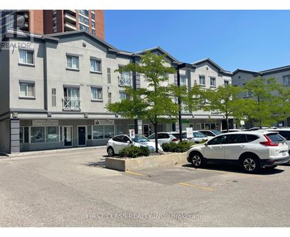 A parking lot in front of a building with a sign that says "First Class Realty Inc. Brokerage.".