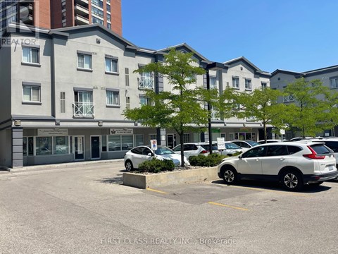 A parking lot in front of a building with a sign that says "First Class Realty Inc. Brokerage.".