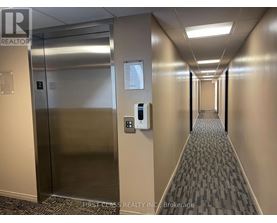 A hallway with a metal elevator and a wall-mounted parking meter.