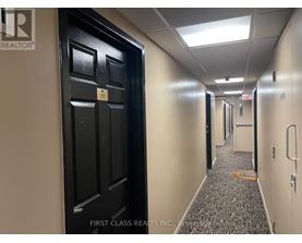 A hallway with a black door on the left and a patterned carpet on the floor.
