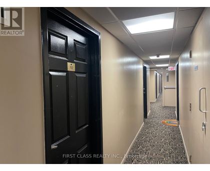 A hallway with a black door on the left and a patterned carpet on the floor.