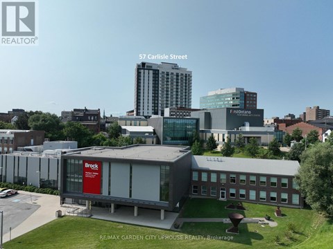 A building with a Brock sign on it is in the foreground of a city scene.
