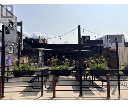 A patio area with tables and chairs and a bar in the background.