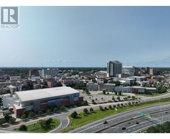 A cityscape with a large building in the foreground and a highway in the background.