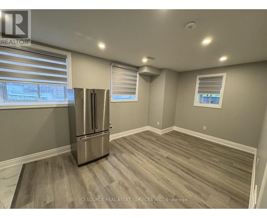 A kitchen with a stainless steel refrigerator and wooden flooring.