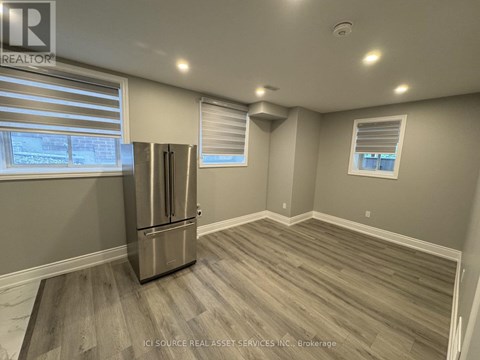 A kitchen with a stainless steel refrigerator and wooden flooring.