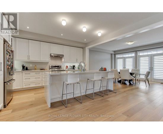 A modern kitchen with white cabinets and a wooden floor.