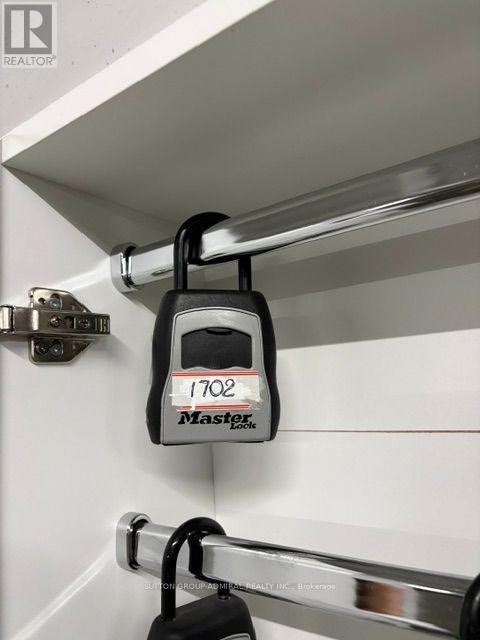 A black Master Lock keyed alike padlock is hanging from a chrome rod.