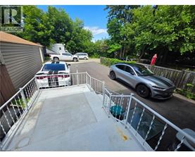 A silver car is parked on a driveway with a white railing.