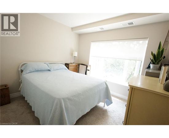 A bedroom with a bed, nightstand, and window.