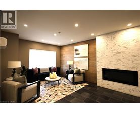 A well-lit living room with a stone fireplace and a patterned rug.