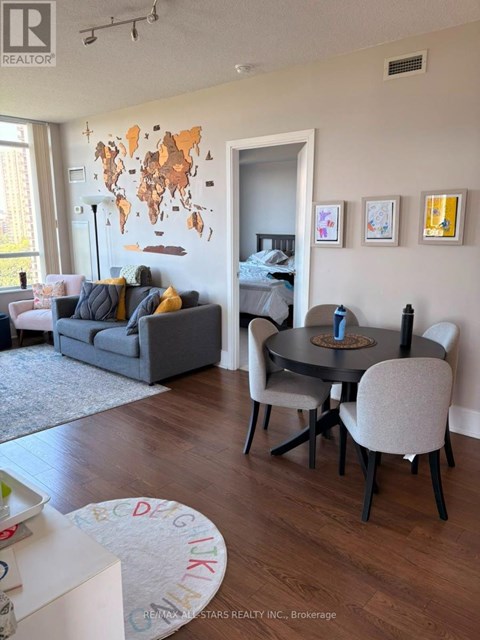A living room with a grey couch, a black table and a world map on the wall.