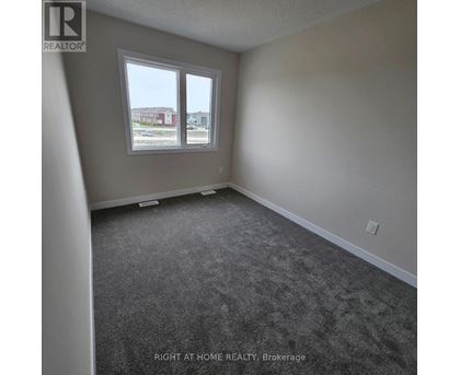 A room with a carpeted floor and a window overlooking a parking lot.