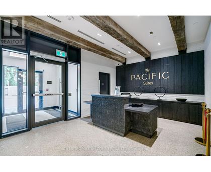 The image shows the front desk of the Pacific Suites with a glass door entrance.