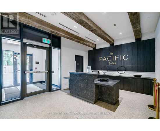 The image shows the front desk of the Pacific Suites with a glass door entrance.