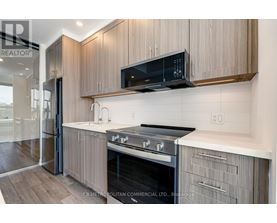 A modern kitchen with wooden cabinets and a black microwave above the stove.