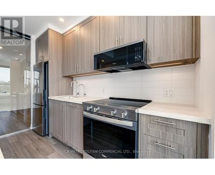 A modern kitchen with wooden cabinets and a black microwave above the stove.