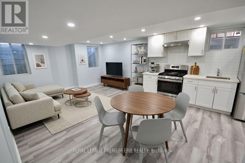 A well-lit kitchen and living room with a dining table and chairs.