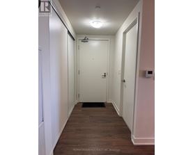 A hallway with a door at the end and a brokerage logo on the wall.