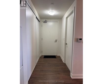 A hallway with a door at the end and a brokerage logo on the wall.