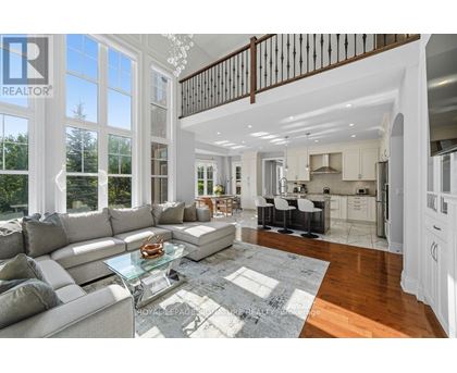 A spacious living room with a glass coffee table and a staircase.