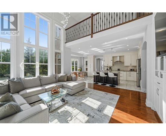 A spacious living room with a glass coffee table and a staircase.