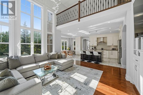 A spacious living room with a glass coffee table and a staircase.