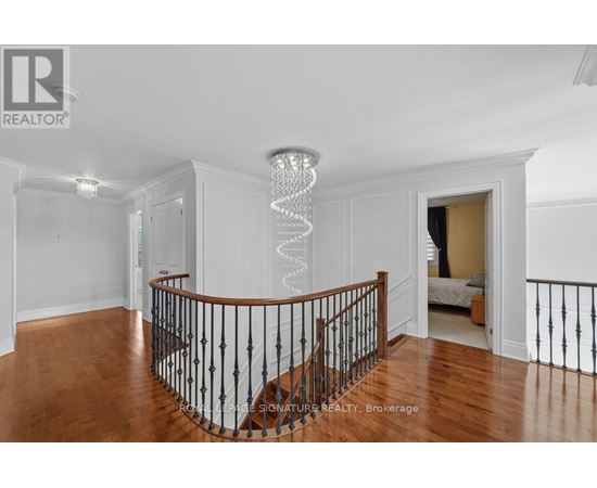 A chandelier hangs from the ceiling in a spacious room with hardwood floors and white walls.