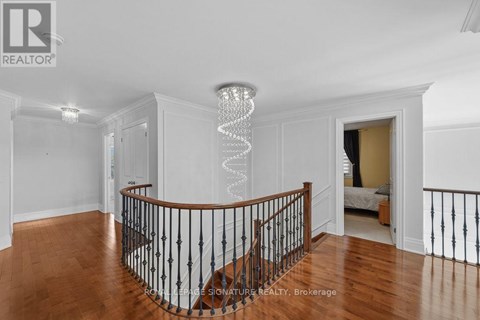 A chandelier hangs from the ceiling in a spacious room with hardwood floors and white walls.