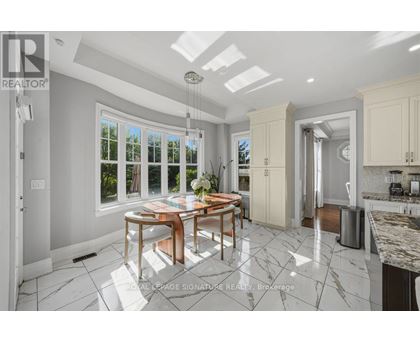 A well-lit kitchen with a dining table and chairs in the middle.