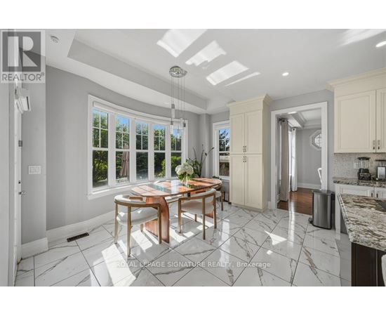 A well-lit kitchen with a dining table and chairs in the middle.