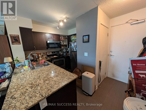 A kitchen with granite countertops and a sign for RE/MAX Success Realty in the background.