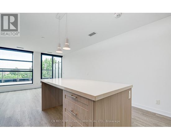 A spacious office room with a large desk and a view of the outdoors through the windows.