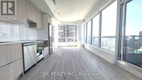 A kitchen with a stainless steel refrigerator and wooden floors.