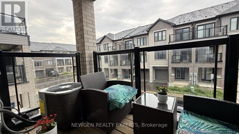 A balcony with a table and chairs overlooking a row of houses.