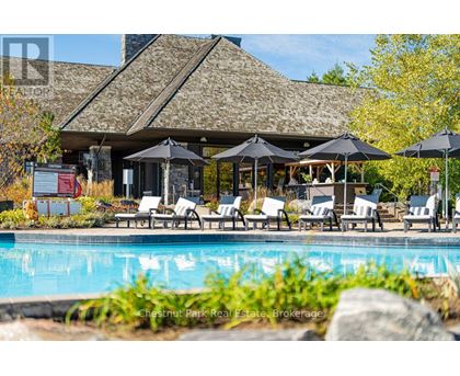 A pool area with a building and umbrella tables.