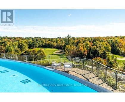 A pool surrounded by a metal fence with a view of a golf course.