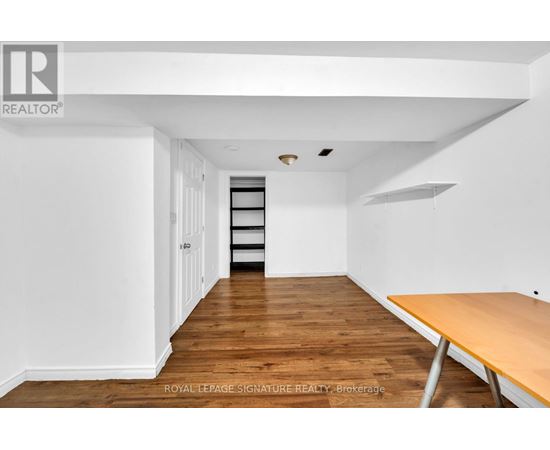A room with a wooden floor and white walls, with a table on the right side.