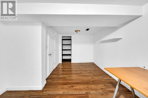 A room with a wooden floor and white walls, with a table on the right side.