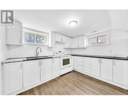 A white kitchen with wooden floors and white cabinets.