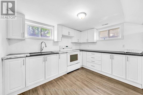 A white kitchen with wooden floors and white cabinets.