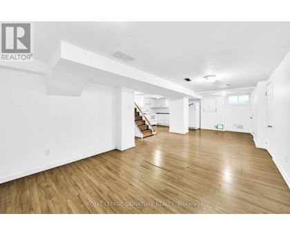A spacious room with wooden flooring and white walls.