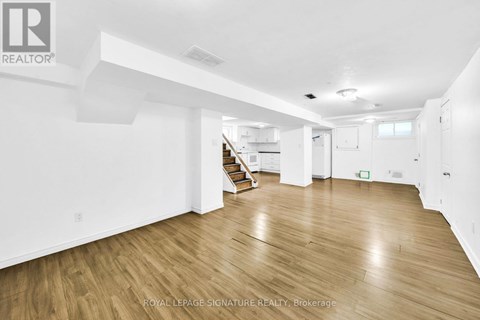 A spacious room with wooden flooring and white walls.